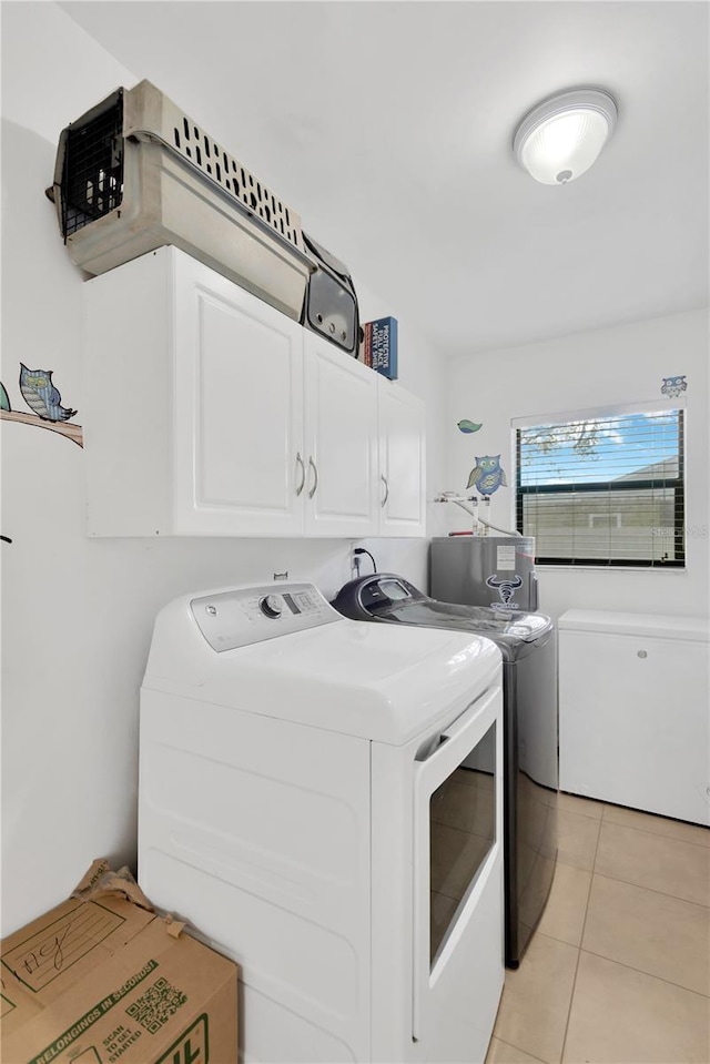 washroom featuring water heater, cabinet space, washing machine and dryer, and light tile patterned floors