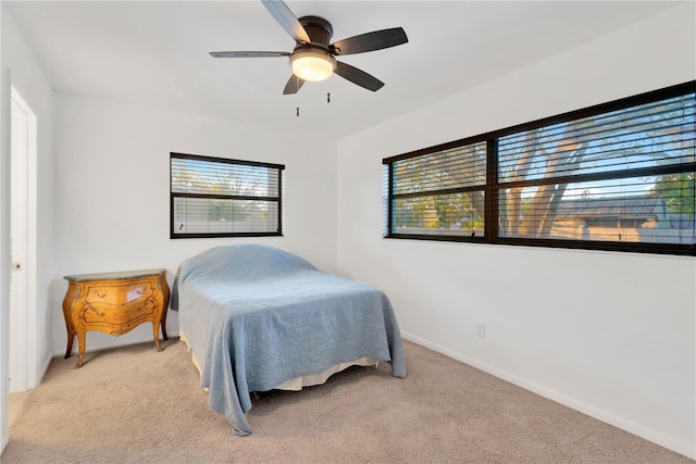 bedroom featuring a ceiling fan, light colored carpet, and baseboards