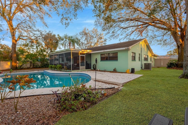 back of house with a fenced backyard, a sunroom, a lawn, a fenced in pool, and stucco siding