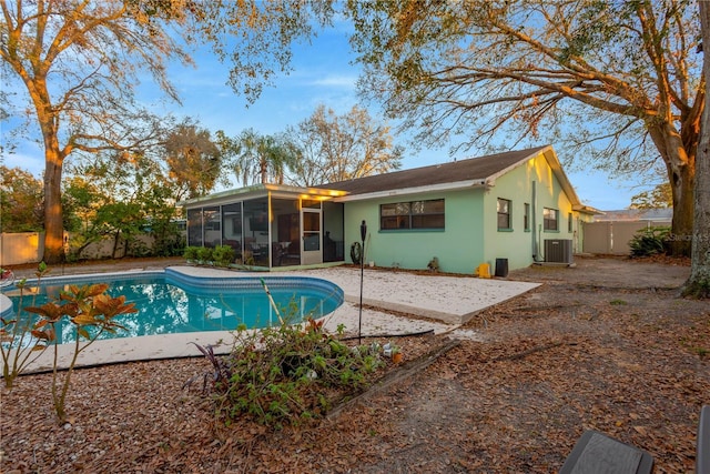 rear view of property with a fenced in pool, a sunroom, a fenced backyard, and a patio