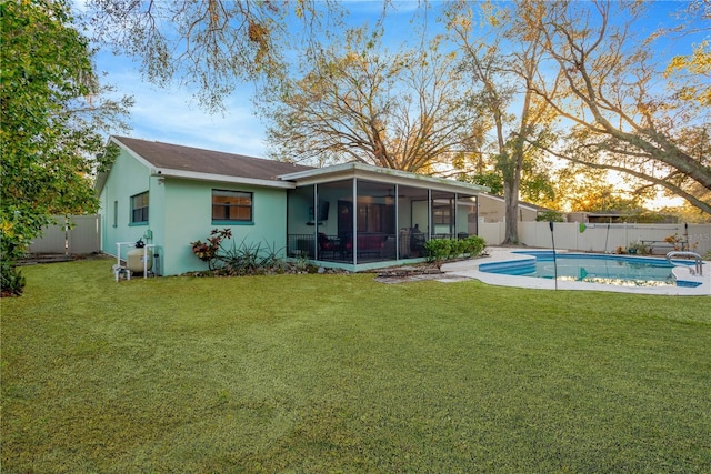 rear view of house with a fenced in pool, a sunroom, a fenced backyard, and a lawn