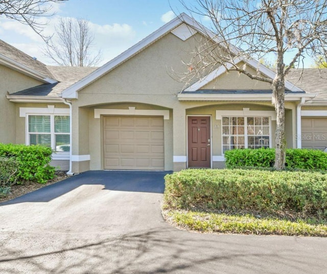 ranch-style home with an attached garage, driveway, roof with shingles, and stucco siding