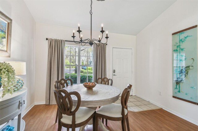 dining space with baseboards, light wood finished floors, and an inviting chandelier