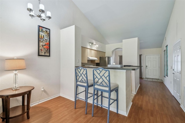 kitchen with a breakfast bar, dark countertops, wood finished floors, and freestanding refrigerator