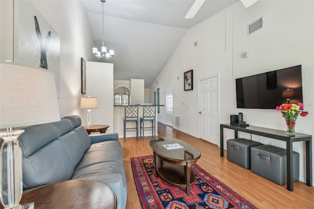 living area with high vaulted ceiling, visible vents, and wood finished floors