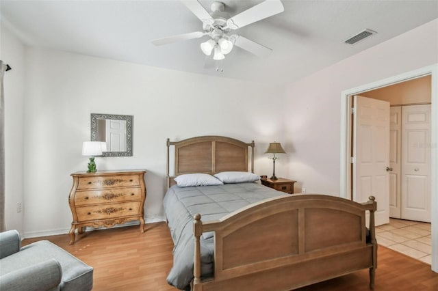 bedroom featuring a ceiling fan, visible vents, and wood finished floors