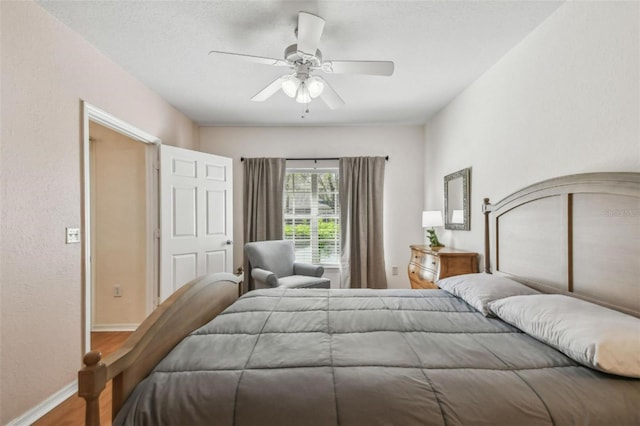 bedroom featuring wood finished floors, a ceiling fan, and baseboards