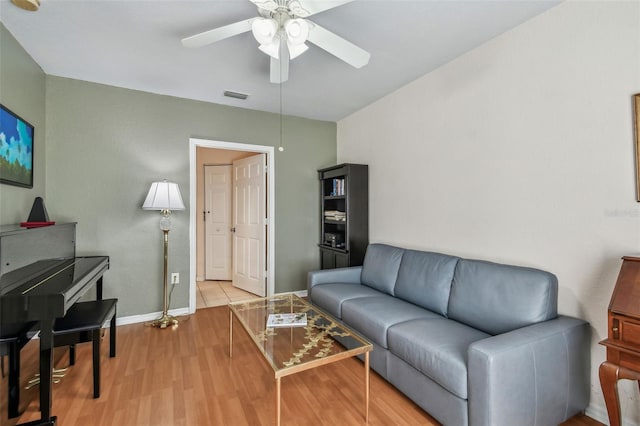 living area featuring a ceiling fan, visible vents, baseboards, and wood finished floors