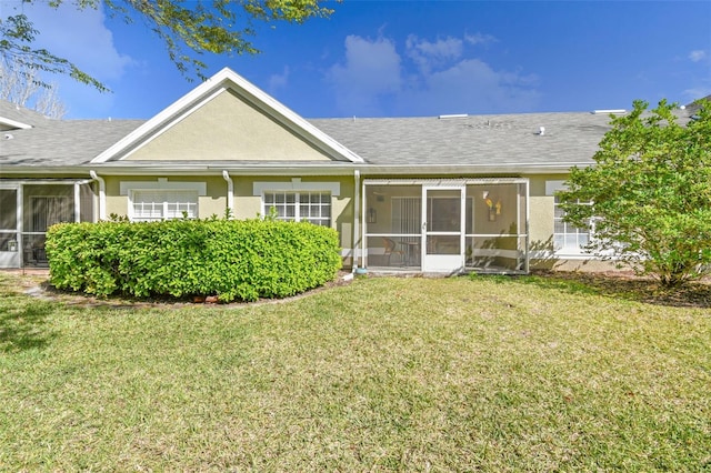 back of house with a yard, a sunroom, and stucco siding