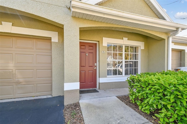 property entrance featuring a garage and stucco siding