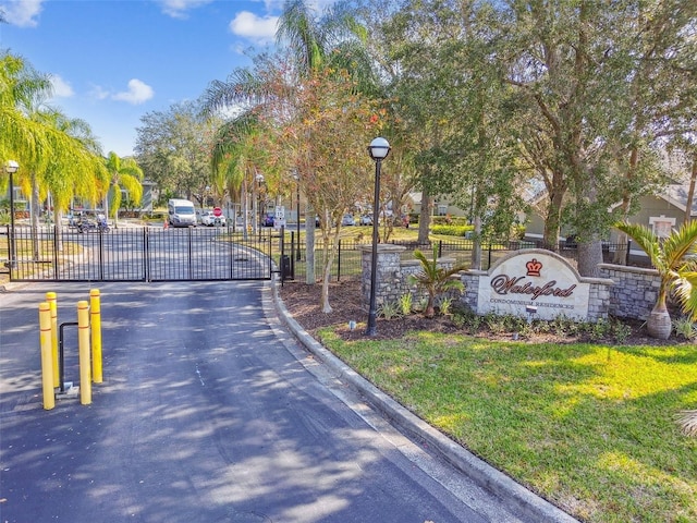 view of road featuring street lights, curbs, a gated entry, and a gate