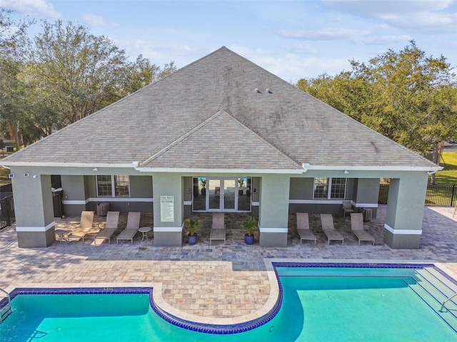 rear view of house featuring a fenced in pool, roof with shingles, a patio, and stucco siding