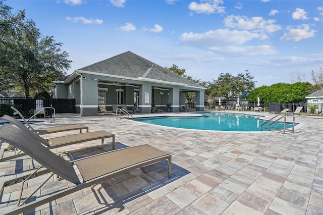 pool featuring an outbuilding, a patio, and fence