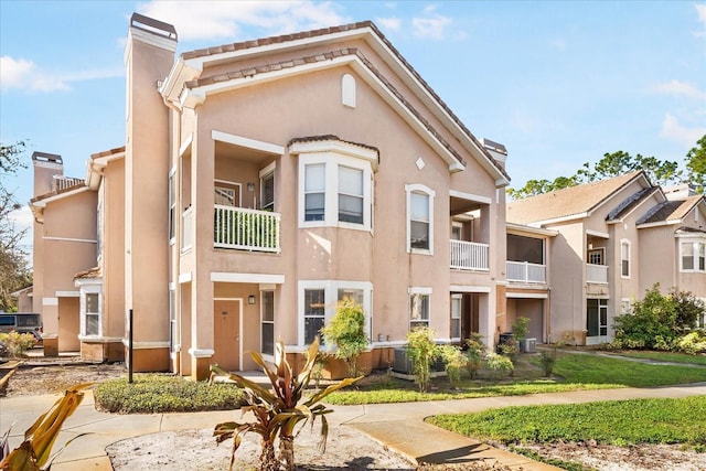 multi unit property featuring central air condition unit, a chimney, and stucco siding