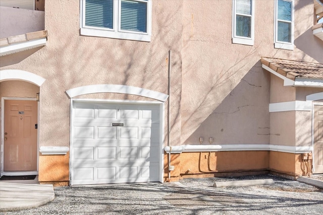 exterior space with an attached garage, a tile roof, and stucco siding