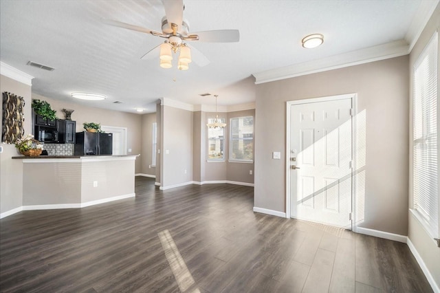 unfurnished living room with dark wood-style floors, ceiling fan with notable chandelier, visible vents, and crown molding