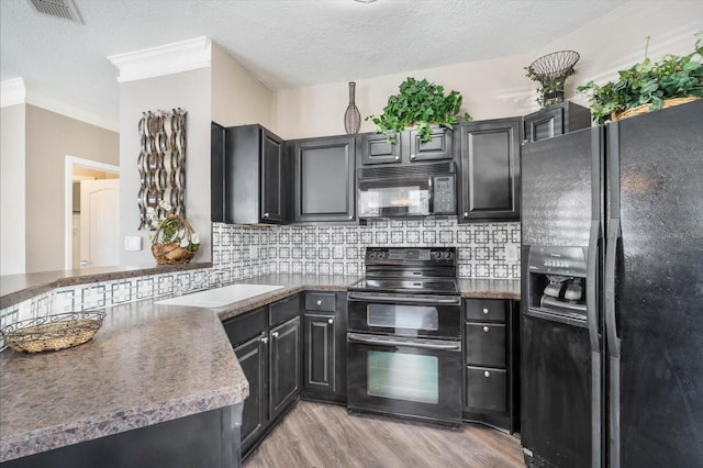 kitchen with a sink, backsplash, black appliances, and light wood finished floors