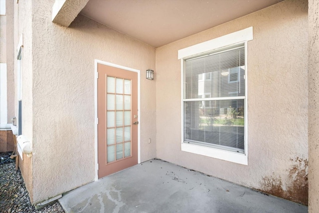 view of exterior entry featuring a patio area and stucco siding