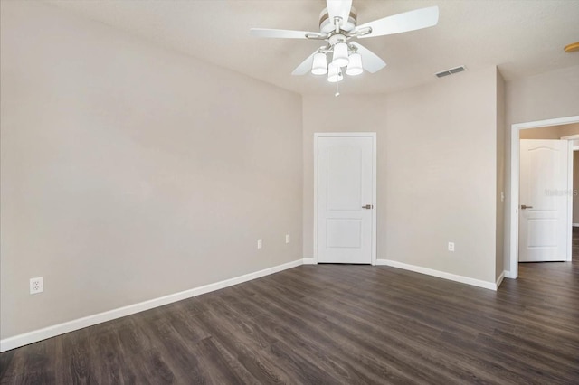 unfurnished bedroom featuring dark wood-style floors, visible vents, baseboards, and a ceiling fan