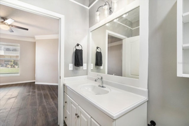 bathroom with ornamental molding, ceiling fan, vanity, wood finished floors, and baseboards