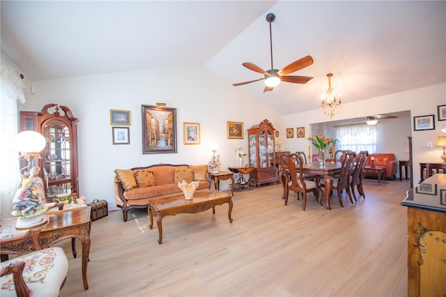 living area with vaulted ceiling, light wood-style flooring, and ceiling fan with notable chandelier