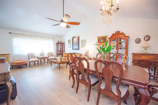 dining area featuring light wood-style flooring, vaulted ceiling, and ceiling fan with notable chandelier