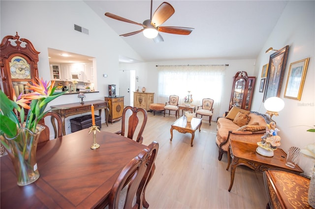 dining area with high vaulted ceiling, light wood-style floors, visible vents, and a ceiling fan