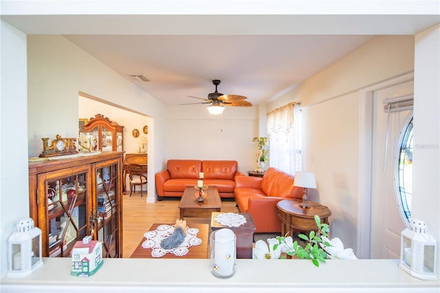 living room with visible vents, wood finished floors, and a ceiling fan