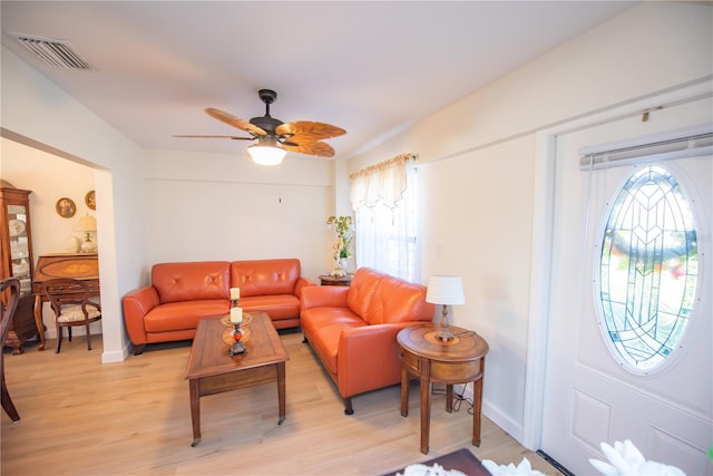 living room featuring ceiling fan, light wood-type flooring, visible vents, and baseboards