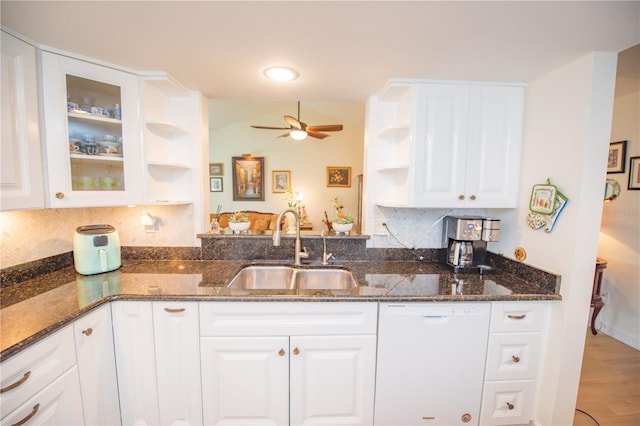 kitchen with white dishwasher, dark stone counters, open shelves, and a sink