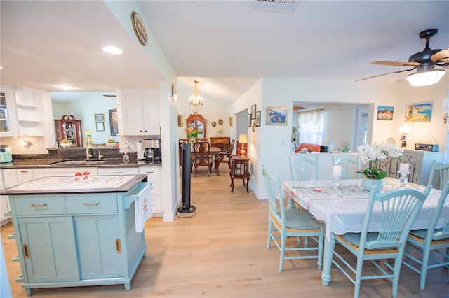 kitchen with tasteful backsplash, visible vents, light wood-style floors, a sink, and ceiling fan with notable chandelier