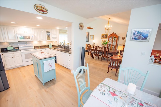 kitchen featuring a center island, light wood-style floors, white cabinetry, a sink, and white appliances