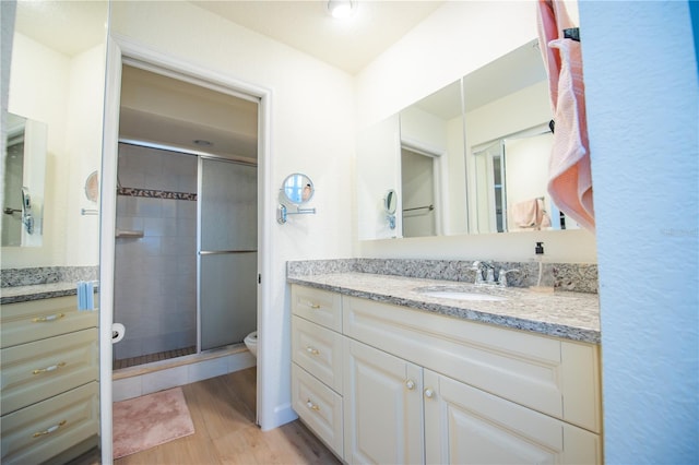 full bathroom with toilet, a stall shower, wood finished floors, and vanity