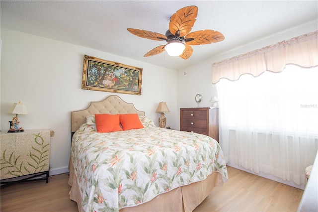 bedroom with light wood-type flooring, ceiling fan, and a textured ceiling