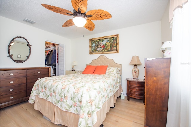 bedroom featuring a textured ceiling, visible vents, a spacious closet, a closet, and light wood finished floors