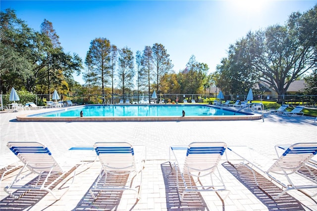 pool with a patio area and fence