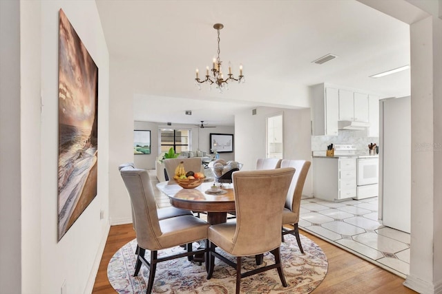 dining room with light wood-style floors, visible vents, and a notable chandelier