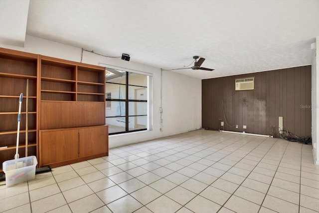 unfurnished living room with light tile patterned floors, ceiling fan, wooden walls, and a wall mounted AC