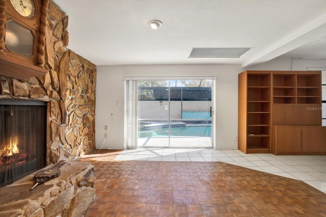 unfurnished living room with visible vents, a stone fireplace, and tile patterned floors