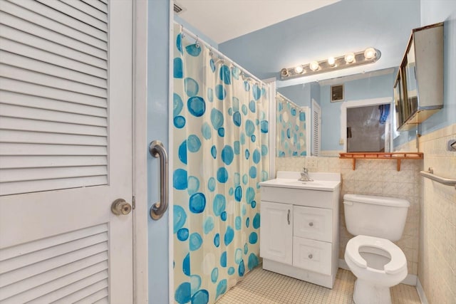 bathroom featuring curtained shower, tile patterned flooring, toilet, vanity, and tile walls