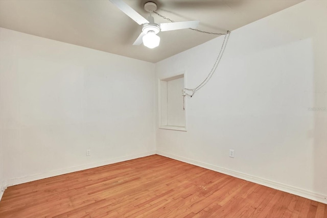 spare room featuring light wood-type flooring, a ceiling fan, and baseboards