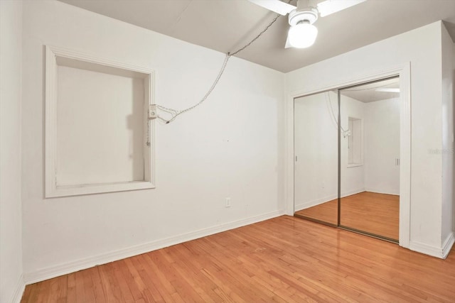 unfurnished bedroom featuring a ceiling fan, a closet, baseboards, and hardwood / wood-style floors