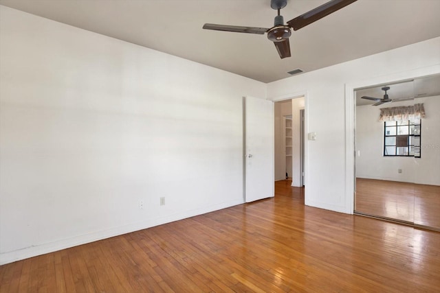 unfurnished bedroom featuring baseboards, visible vents, ceiling fan, and hardwood / wood-style floors