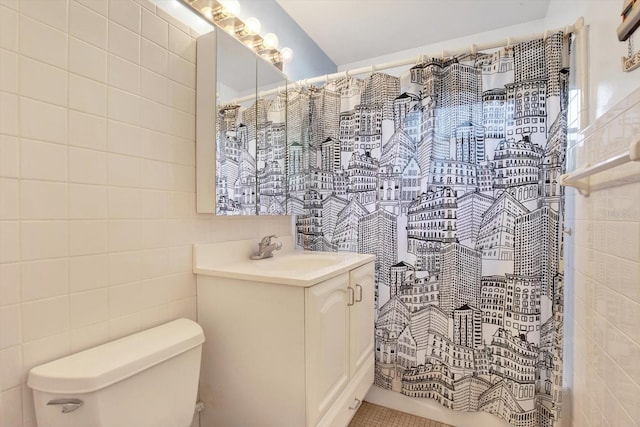 bathroom with toilet, curtained shower, vanity, and tile walls