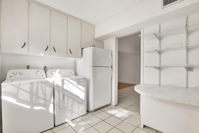 clothes washing area featuring washer and dryer, visible vents, cabinet space, and light tile patterned floors