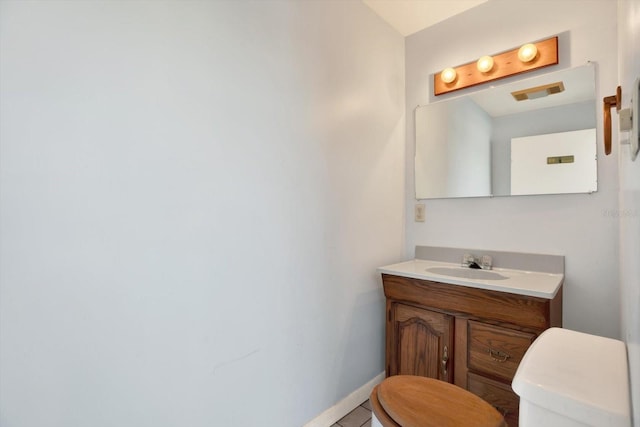 half bath featuring baseboards, vanity, and toilet