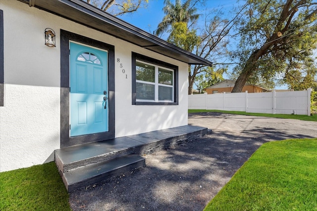 entrance to property with fence and stucco siding