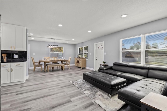 living room with baseboards, recessed lighting, light wood-type flooring, and a healthy amount of sunlight