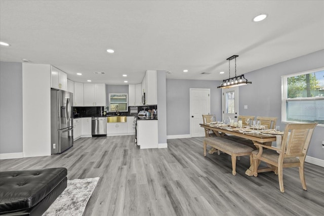 dining area featuring light wood finished floors, recessed lighting, and baseboards