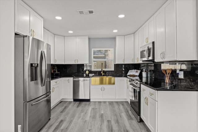 kitchen featuring dark countertops, visible vents, stainless steel appliances, and a sink